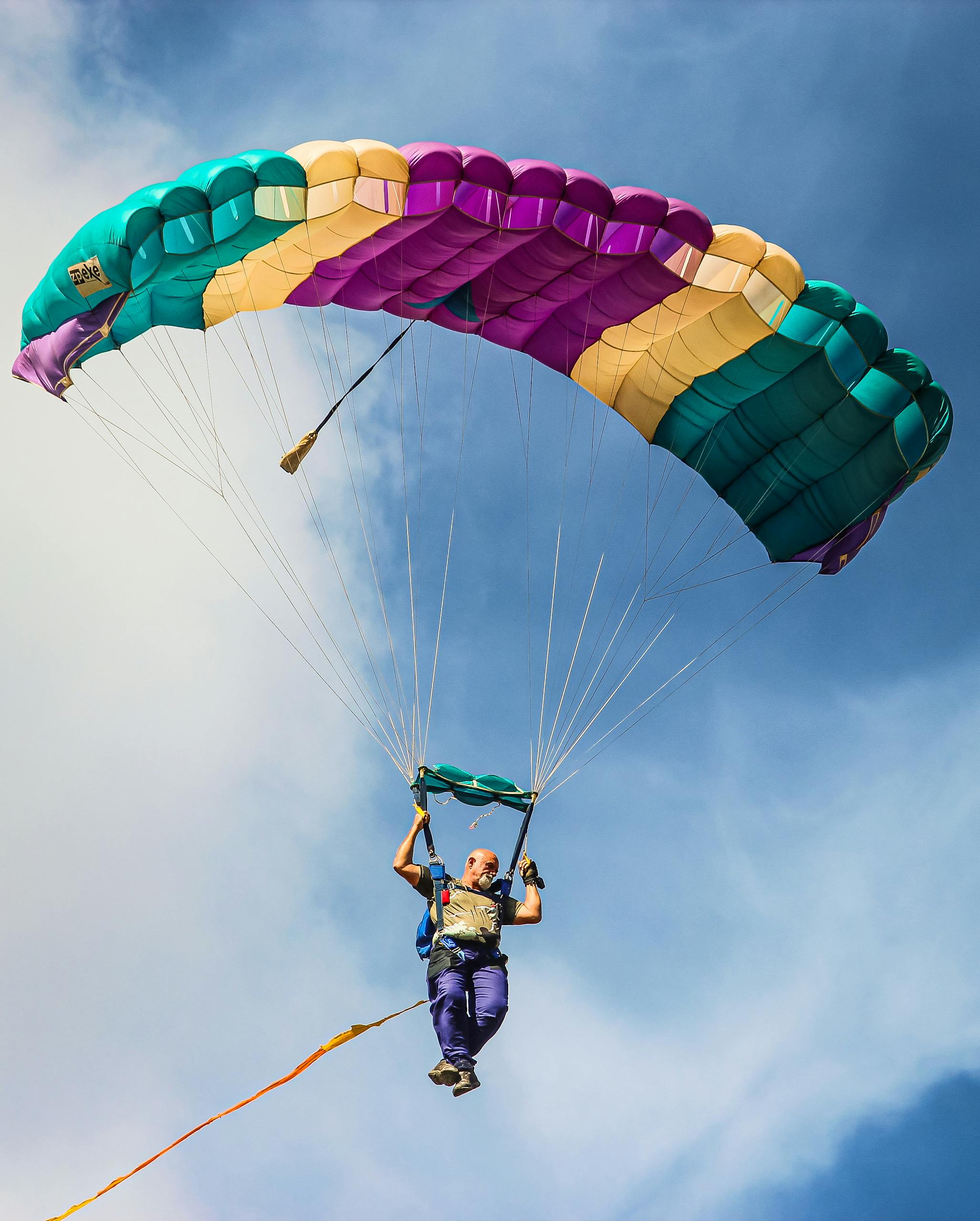 A vibrant parachutist gliding through blue skies, capturing the thrill of skydiving.